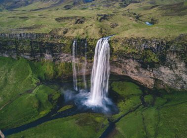 دانلود عکس هوایی از آبشارها بر فراز مرتع سبز در طول روز