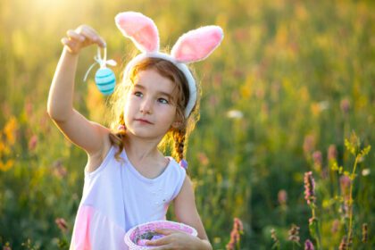 دانلود عکس دختر بامزه بامزه با تخم مرغ های رنگ شده عید پاک در بهار در طبیعت