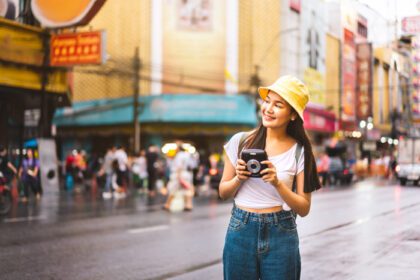 دانلود عکس زن مسافر آسیایی دوربین فوری را در دست بگیرید