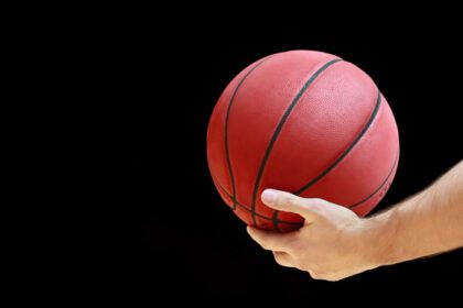 دانلود عکس توپ بسکتبال در دست مرد در پس زمینه مشکی