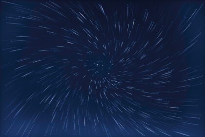 دانلود عکس انتزاعی نوردهی طولانی از مسیرهای گردابی ستاره پس زمینه آبی رنگی
