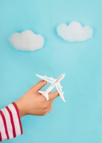 دانلود عکس دست های کودک که یک هواپیمای اسباب بازی را در دست دارند مفهوم سفر بر فراز ابرها