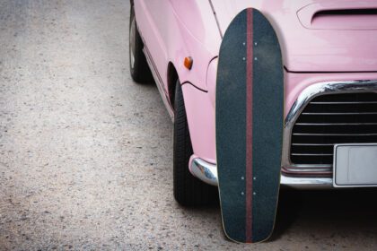 دانلود عکس اسکیت سواری قدیمی با ماشین صورتی رنگ در جاده در پارکینگ