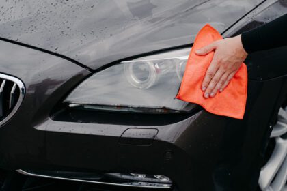 دانلود عکس مرد دست پاک کردن چراغ جلو ماشین با پارچه میکروفایبر