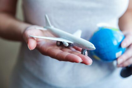 دانلود عکس دست های زن که مدل اسباب بازی های کوچک هواپیما و کره را در دست دارند