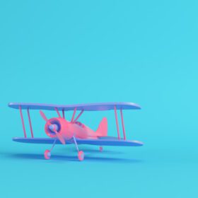 دانلود عکس هواپیمای دوبال صورتی در پس زمینه آبی روشن در رنگ های پاستلی