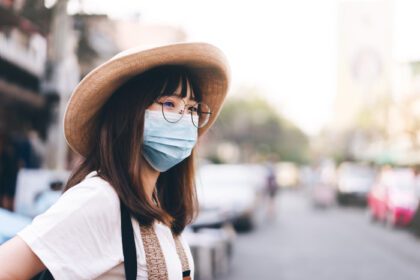 دانلود عکس دختر جوان مسافرتی آسیایی با کلاه و ماسک محافظ