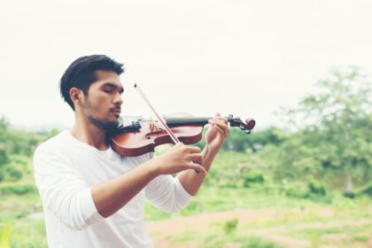 دانلود عکس نوازنده جوان هیپستر مرد نوازنده ویولن در طبیعت در فضای باز