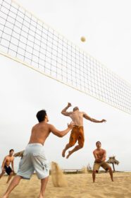 دانلود عکس دوستان مرد در حال بازی والیبال در ساحل