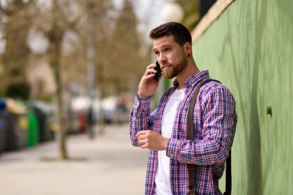 دانلود عکس مرد جوان در حال صحبت با تلفن هوشمند خود در پس زمینه شهری