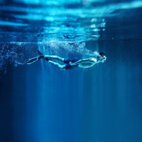 دانلود عکس مرد غواصی در پس زمینه آبی نمای زیر آب
