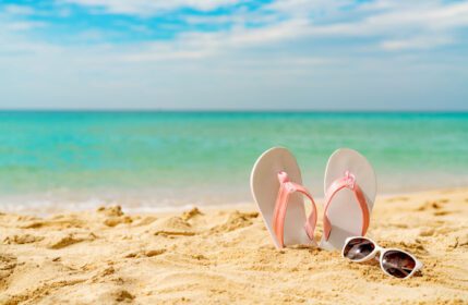 دانلود عکس عینک آفتابی صندل صورتی و سفید در ساحل شنی در کنار دریا