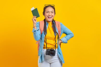 دانلود عکس پرتره مسافر جوان شاد آسیایی که پاسپورت دارد