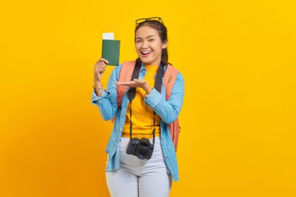 دانلود عکس پرتره مسافر جوان شاد آسیایی در حال نمایش پاسپورت