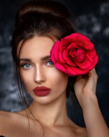دانلود عکس زن جوان زیبا که یک گل رز قرمز در دست دارد