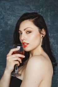 دانلود عکس زن جوان زیبا با لیوان شراب در پس زمینه خاکستری