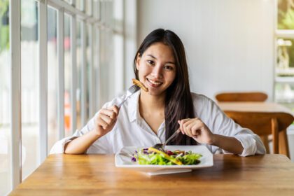 دانلود عکس پرتره زن جوان خندان آسیایی در حال غذا خوردن