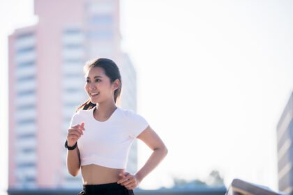 دانلود عکس خندان زن ورزشکار تناسب اندام جوان آسیایی در حال دویدن و
