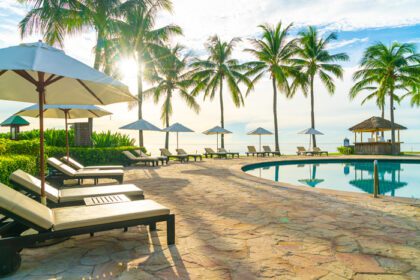 دانلود عکس چتر و صندلی در اطراف استخر در هتل استراحتگاه برای سفرهای تفریحی و تعطیلات در نزدیکی ساحل اقیانوس