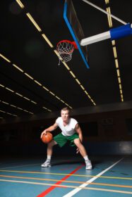 دانلود عکس مرد جوان سالم و سرسخت در حال بازی بسکتبال در سالن بدنسازی سرپوشیده