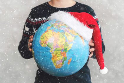 دانلود عکس بچه کریسمس مبارک که کره زمین را با کلاه بابا نوئل در دست دارد