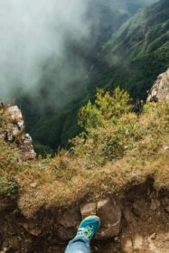 دانلود عکس پا بر روی صخره در لبه صخره های سنگی عمیق با مه در