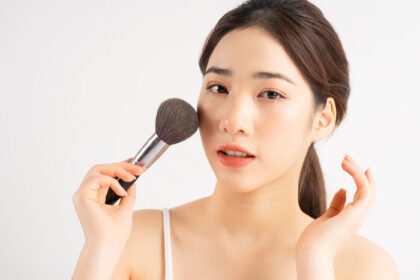 دانلود عکس دختر جوان آسیایی که براش آرایش را برای خودش در دست گرفته است