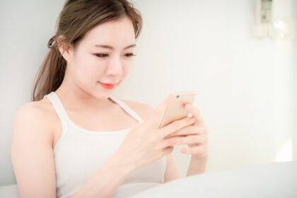 دانلود عکس نگاه دختر جوان آسیایی زیبا به تلفن همراه هوشمند