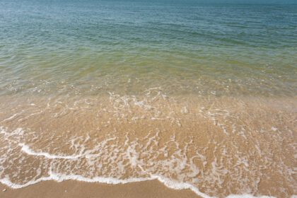 دانلود عکس موج نرم اقیانوس از اقیانوس آبی در ساحل شنی گرمسیری در